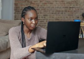 Young black woman sitting at her laptop on a virtual therapy session at home
