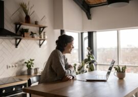 Woman sitting at kitchen counter while chatting on a laptop in a video call