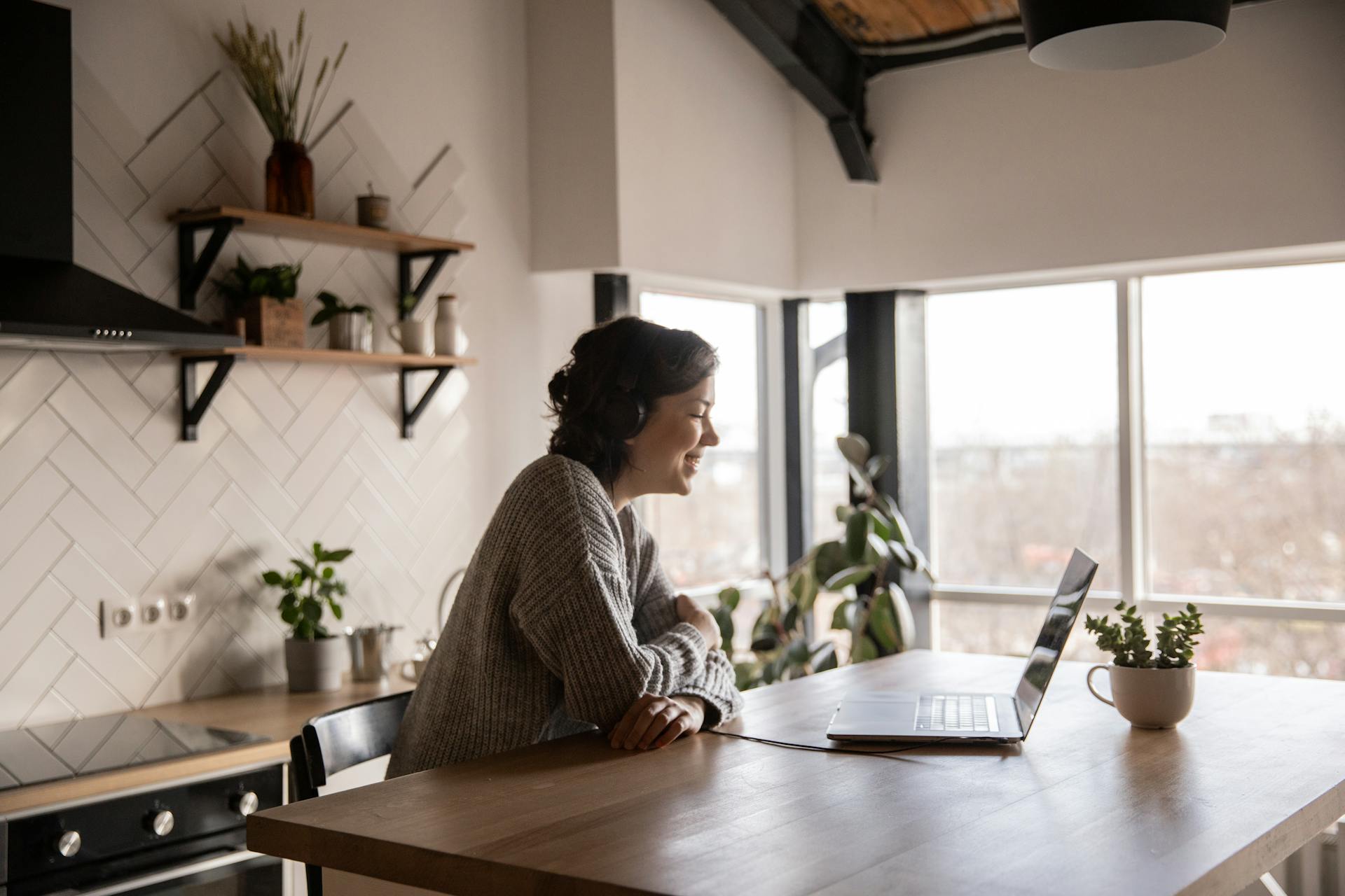 Woman sitting at kitchen counter while chatting on a laptop in a video call