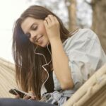 Young woman smiling while listening to music through earphones