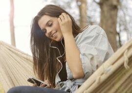 Young woman smiling while listening to music through earphones