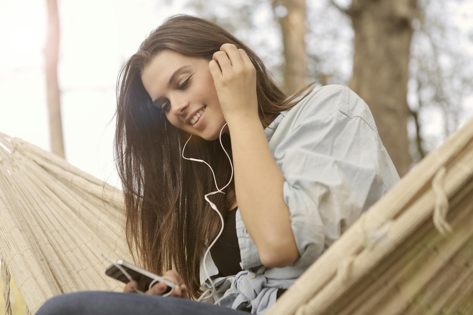 Young woman smiling while listening to music through earphones